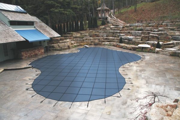 Underground pool covered by blue safety cover in Winter