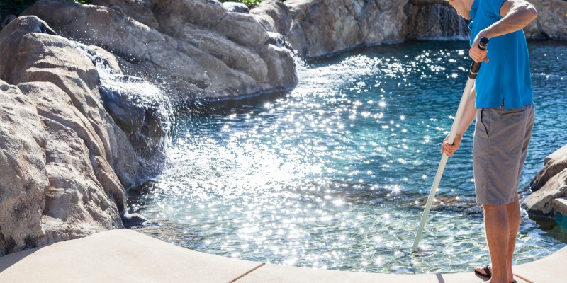 Man cleaning pool with leaf net