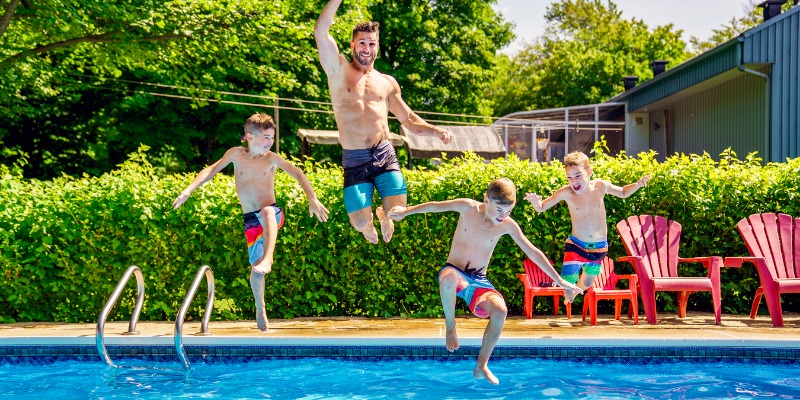 Dad and sons jumping into pool